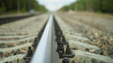 a close-up view of camera moving away from the railroad track stretching into the distance, the shoot focuses on the rail and its fastenings, with the background beautifully blurred, with