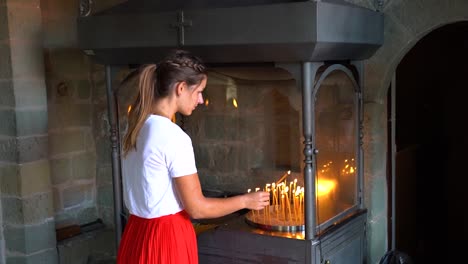 una mujer enciende una vela en un monasterio.