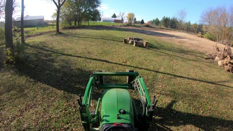 Punto-De-Vista-De-Gran-ángulo-Sobre-Un-Pequeño-Tractor-Verde-Que-Conduce-Maniobrando-Hacia-Un-Montón-De-Tocones