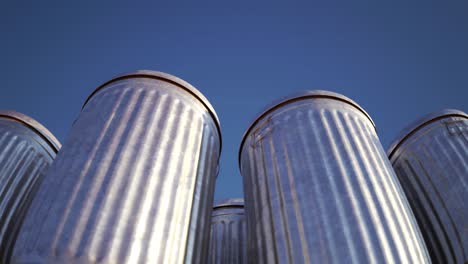 Steel-trash-bins-stacked-together-in-an-endless-loop.-Sunlight-illuminates-shiny-metal-lids-on-a-vast-field-full-of-containers-with-garbage-waste.-Symbol-of-growing-pollution-and-rubbish-outgrowth.