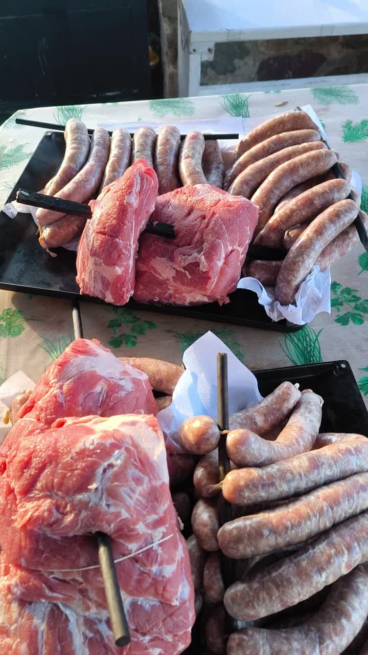 Vertical close up of raw pork and fresh sausages prepared for smoking, threaded on metal rods and arranged on trays. Traditional homemade meat preparation before smoking process
