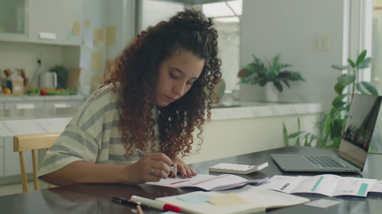 Girl Examining Bills and Counting Expenses with Calculator at Home