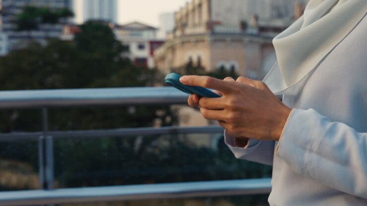 Close-up of person's hands using a smartphone outdoors in a city setting