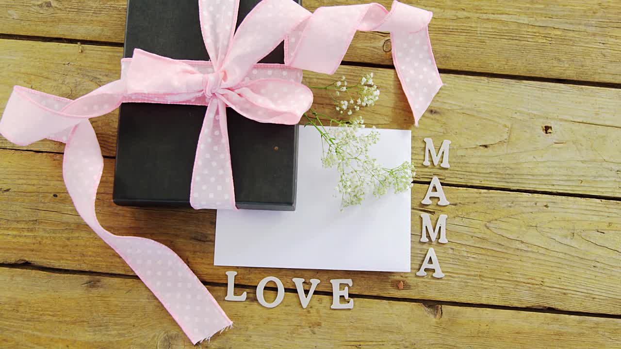 Scatola regalo con la scritta "mama love" su tavola di legno