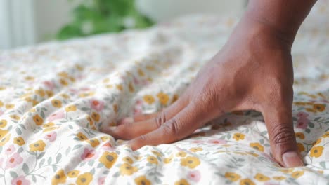 person's hand on floral bedding