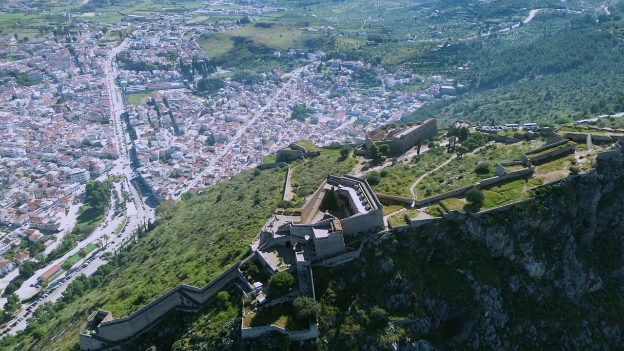 Ripresa cinematografica 4K con drone che panoramica a sinistra dal Castello di Palamidi per rivelare un panorama mozzafiato della città di Nauplia. Architettura storica europea, tetti rossi e paesaggio costiero in Grecia