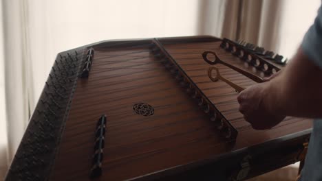 instrumento de música clásica de madera dulcimer, primer plano de cuerda de martilleo masculino de manos caucásicas, músico profesional