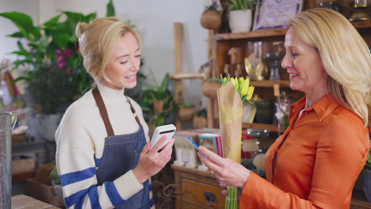 Female Customer In Florists Shop Making Contactless Payment For Flowers With Card