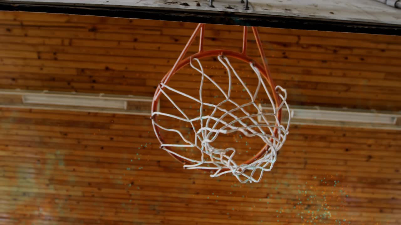 남자 농구 선수가 스포츠 체육관에서 드리블하며 무릎을 굽혀 덩크슛을 날려 득점하고 있어요.