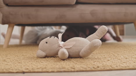 kids crawling under couch for toy-bear