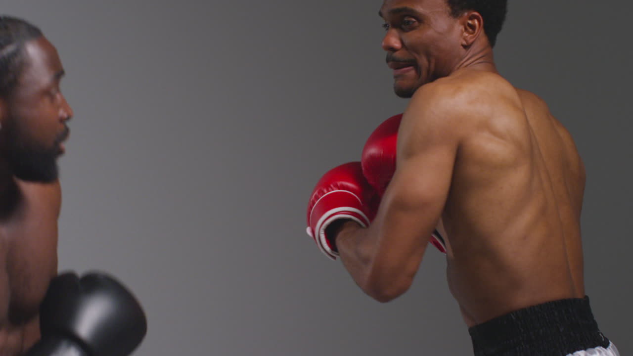 fotografía de estudio de cerca de dos boxeadores masculinos con guantes luchando en un partido de boxeo contra un fondo gris 1