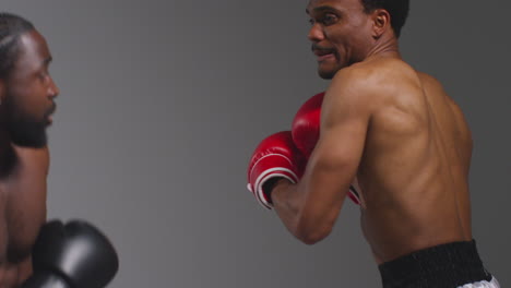 Close-Up-Studio-Shot-Of-Two-Male-Boxers-Wearing-Gloves-Fighting-In-Boxing-Match-Against-Grey-Background-1