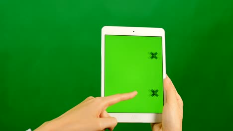 mujer de negocios usando una tableta de pantalla verde en blanco sobre un fondo verde.
