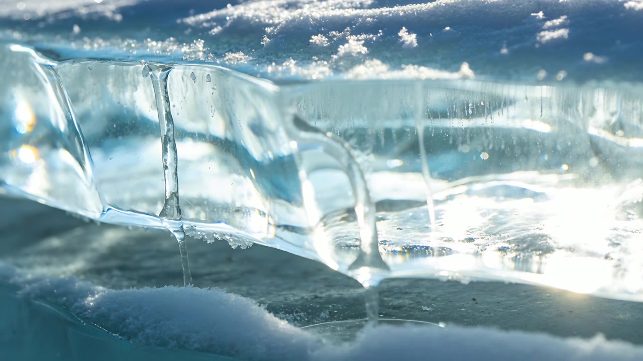 Sunlight warming translucent ice ledge, forming meltwater filaments, pinching off droplets