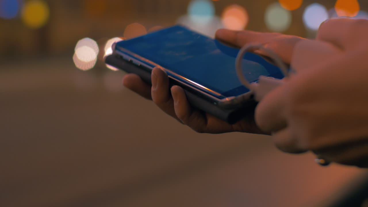 mujer cargando su teléfono inteligente con un banco de energía