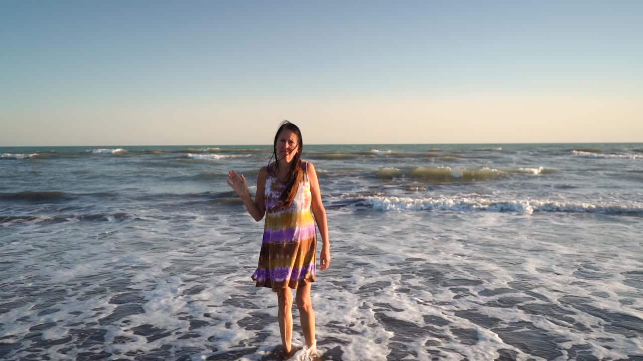 Lonely Woman At The Beach Bidding Goodbye While Walking Backward To The Sea. Suicidal Concept. dolly-out