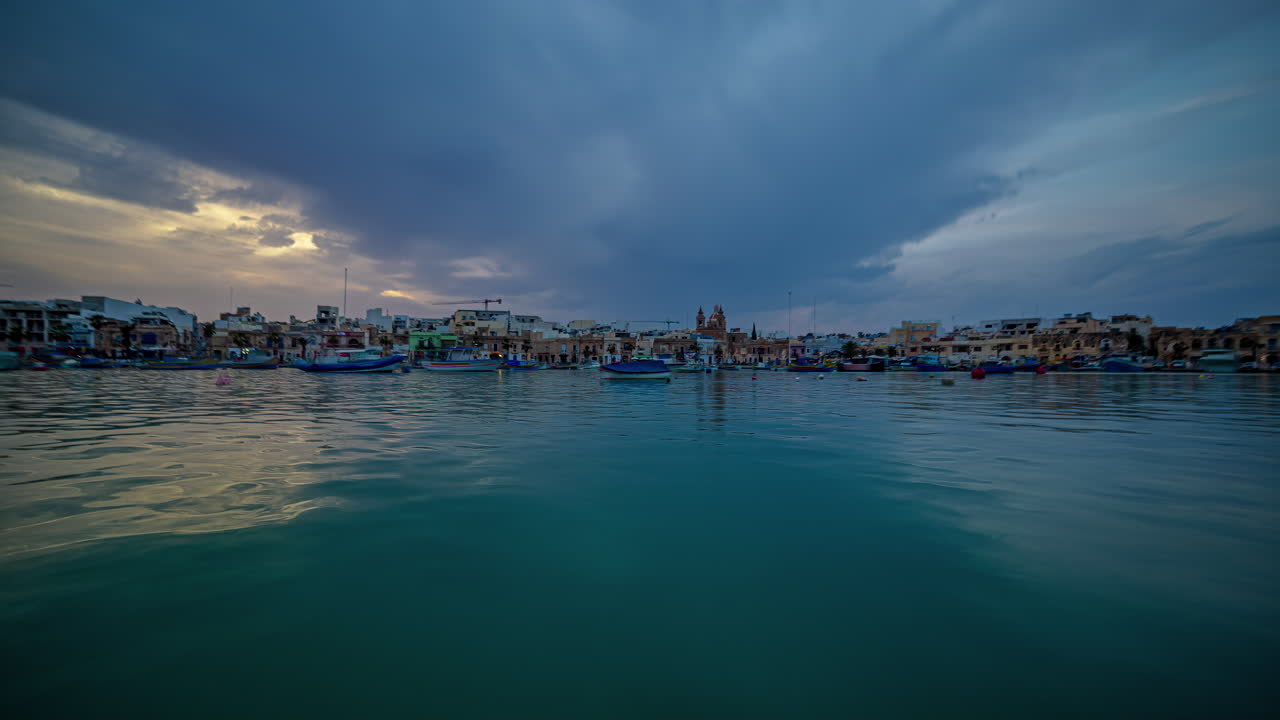 marsaxlokk, malta con un paisaje de nubes crepusculares mirando a través de una hermosa bahía - lapso de tiempo