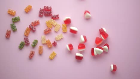 colorful gummy bears and candies on pink background