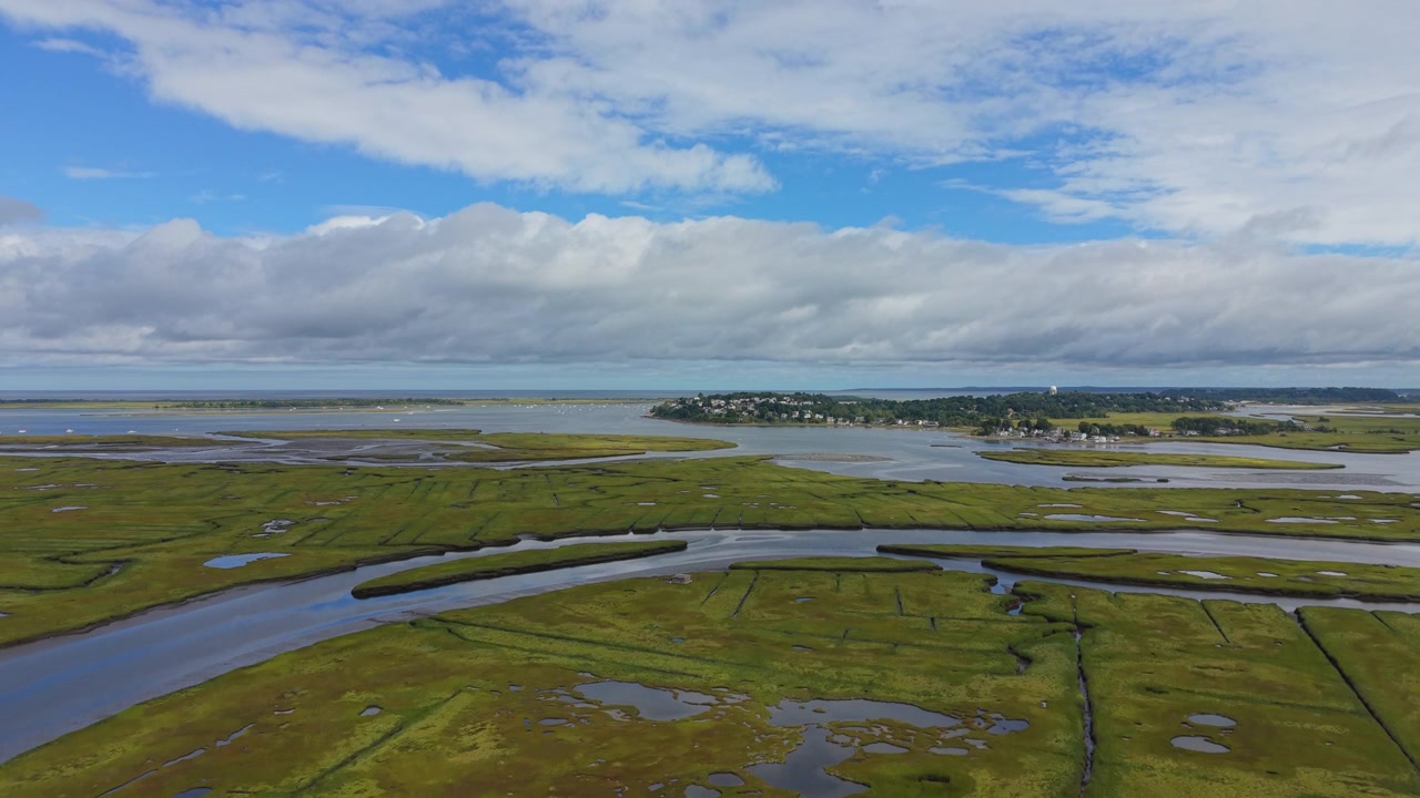 Vista aerea in discesa su tortuosi canali di marea e una verde palude salmastra verso un piccolo villaggio costiero e l'Oceano Atlantico a Ipswich, vista mozzafiato nel Massachusetts
