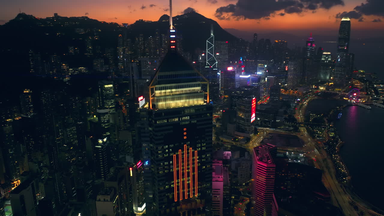 toma panorámica de drones aéreos del horizonte de hong kong con el edificio de la plaza central en primer plano y el distrito central y la cordillera en el telón de fondo durante un resplandor cinematográfico y colorido de la puesta de sol