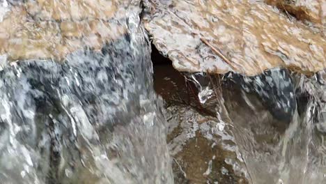 flowing-waterfall-from-a-mountain-spring-water-stream-running-down-huge-sandstone-slabs-of-rock-with-green-moss,-crystal-clear-drinking-water,-meditate-tranquil-and-peaceful-calm-slow-motion-footage