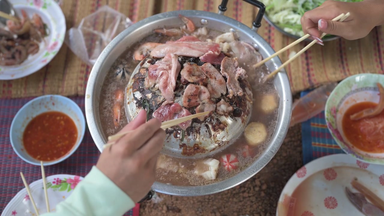 มื้อค่ำหมูกระทะบาร์บีคิวแบบไทยแท้กับเพื่อนๆ กลางแจ้ง การรวมตัวสังสรรค์อาหารริมทางแบบดั้งเดิม ภาพมุมสูง