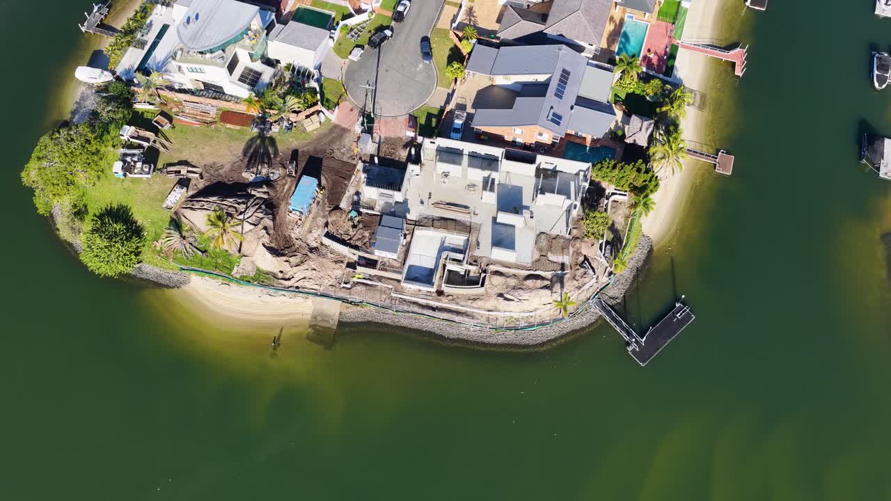 Drone footage captures construction activity near water in Gold Coast, Australia, highlighting development and luxury housing
