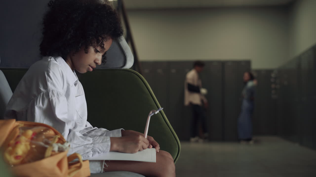 African teen student drawing sketches on school break. Schoolgirl sitting alone.