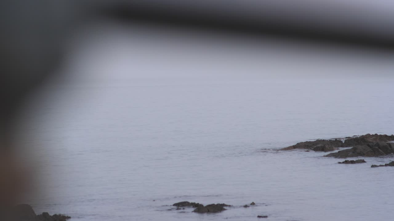 잔잔한 물과 형형색색의 하늘이 있는 일출 시 바다와 해변 마을의 안개