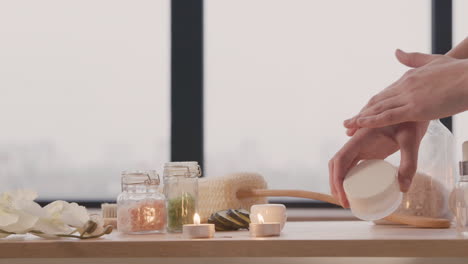 camera focuses on wooden table with bathroom elements and the hands of a woman smearing cream