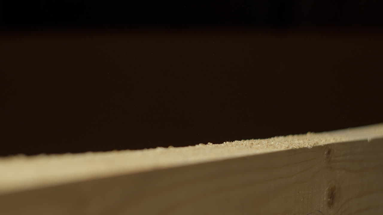 High quality video showing a craftsman sanding a wooden board in warm light with slow smooth hand movements and fine dust in the air creating a rich tactile workshop atmosphere
