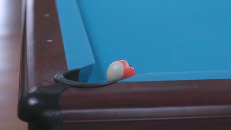 man missing pool ball shot in corner pocket on blue billiards table