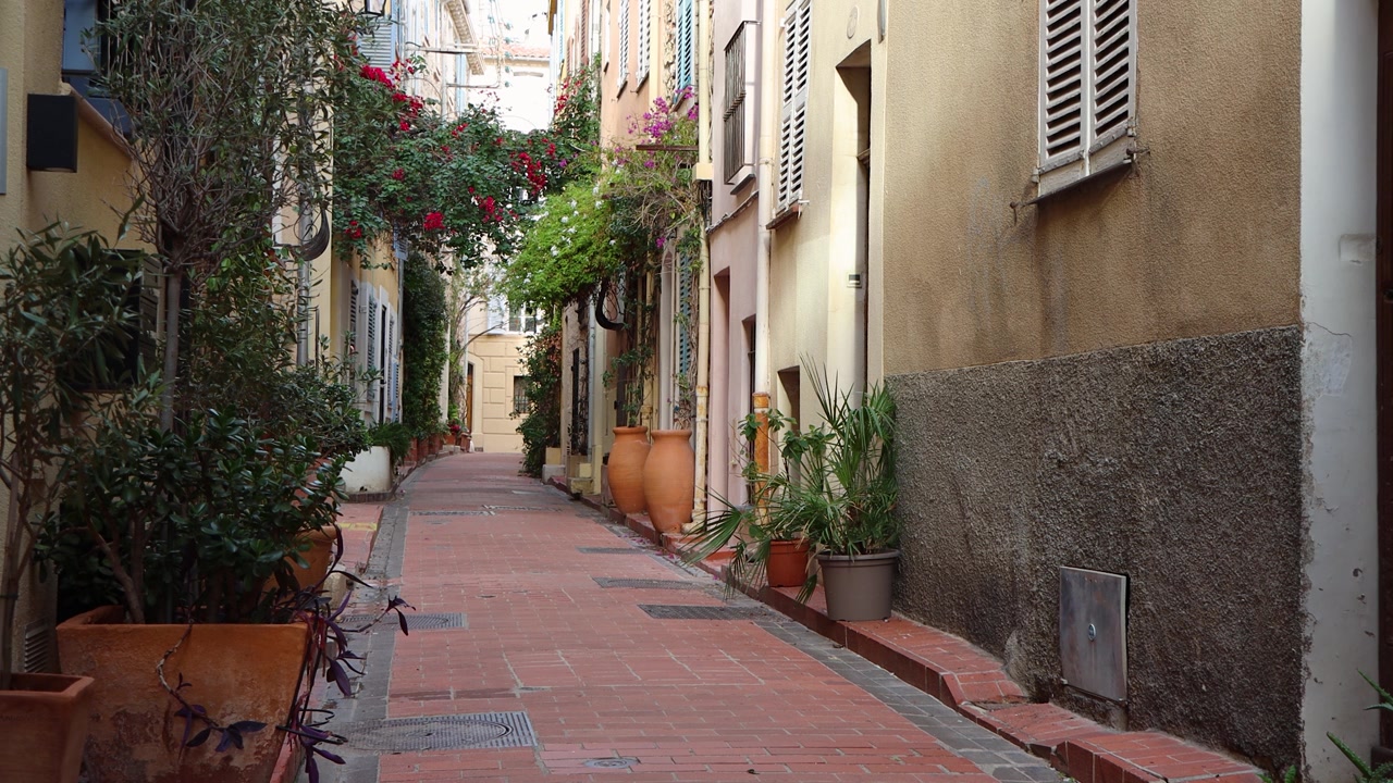 Vicolo stretto e tranquillo con piante in vaso e persiane ad Antibes.