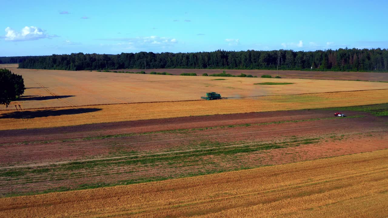 Panoramaansicht goldener Felder mit Mähdrescher in der Ferne
