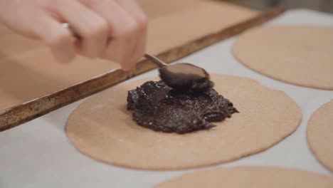 spreading plum filling on a galette pastry, close up