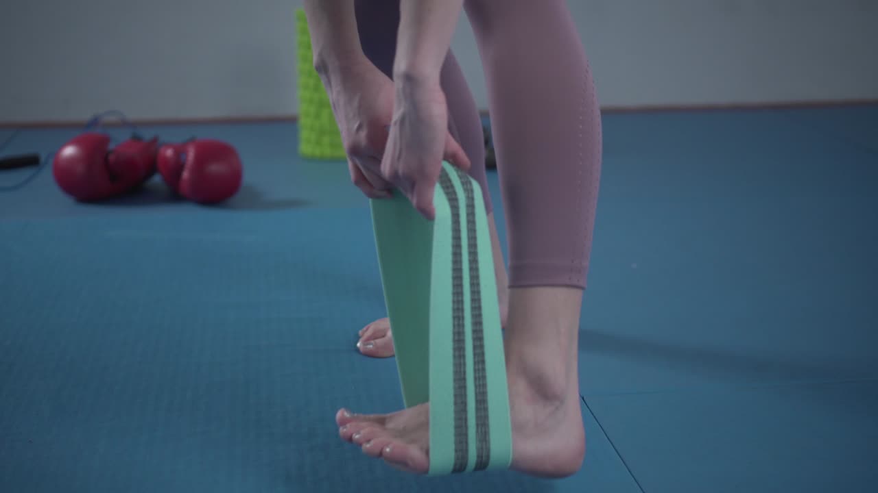 piernas mujer descalza haciendo ejercicio de pilates con banda de resistencia de tela elástica. bandas de resistencia para el trasero y las piernas, bandas de ejercicio trabajando, estiramiento, terapia física. bandas elásticas para el fitness.