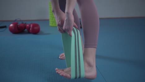 legs woman barefoot doing pilates exercise with elastic fabric resistance band. resistance bands for butt and legs, exercise bands working out, stretching, physical therapy. elastic bands for fitness.