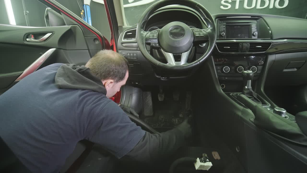 Professional car cleaning. Сar wash. Interior detailing. Dry clean and detail a car interior. Deep seats cleaning. Wiping foam in car wash. Cleaning the car panel from dust. A vacuum cleaner