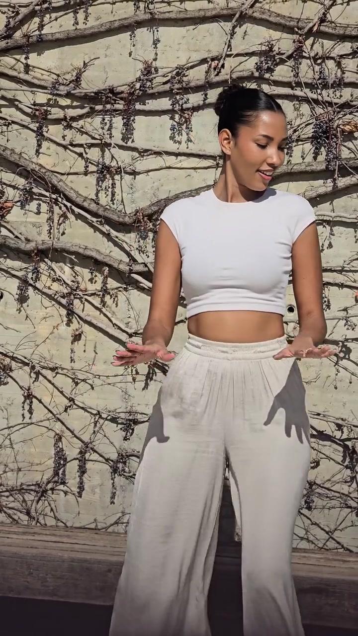Una giovane donna elegante che posa con grazia contro uno sfondo murale artistico e colorato.