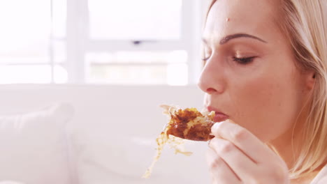 Mujer-Sentada-En-Un-Sofá-Comiendo-Una-Pierna-De-Pollo