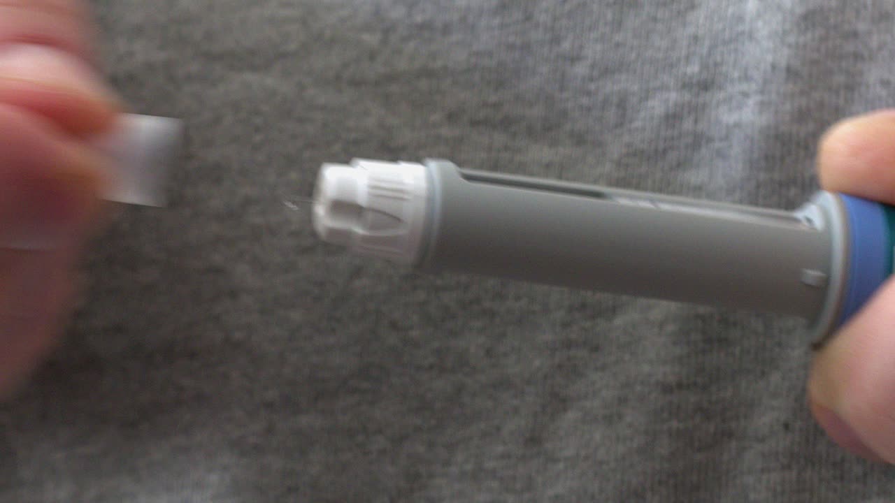 Cap is removed from sharp medication needle, drop of drug on tip