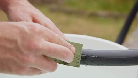 hand using sandpaper to rough up punctured bicycle tire