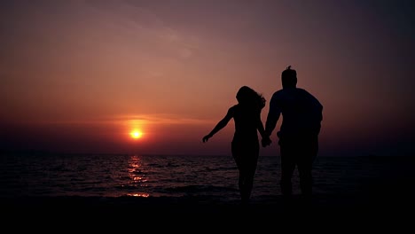 Ein-Paar-Rennt-Am-Strand-Entlang-Und-Blickt-In-Zeitlupe-Auf-Das-Meer-Von-Der-Rückseite