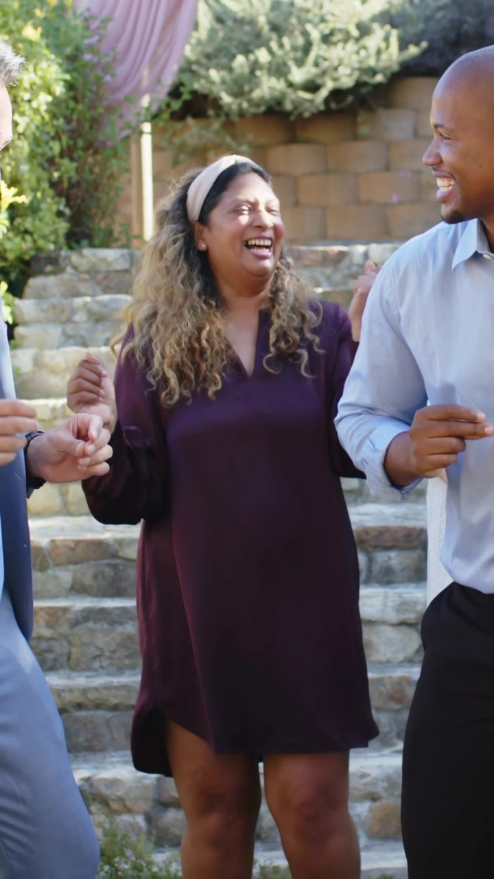 Man in gray suit shaking hands, sparking group dancing, celebrating events in garden by stone steps
