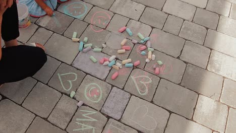 a mother and her child draw with chalk on the ground in front of their home