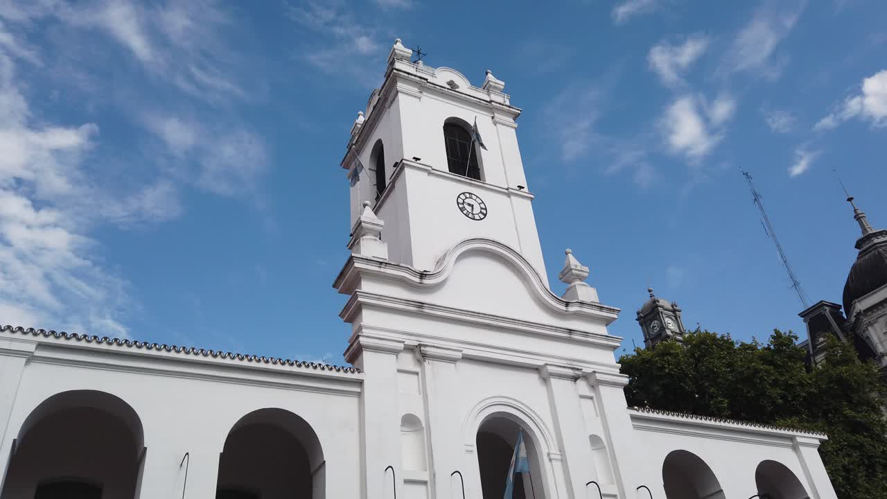 Rivelazione con inclinazione verso il basso della Torre dell'Orologio e del Cabildo, storico edificio governativo coloniale con bandiere, a Buenos Aires, Argentina