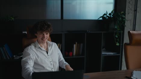 Happy-young-guy-with-curly-hair-in-a-white-shirt-shaking-hands-with-an-experienced-colleague-during-the-start-of-an-interview-in-the-office