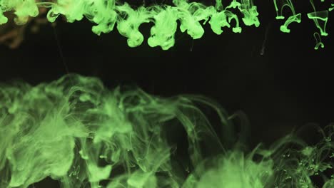 slow motion video of green watercolor ink mixing in water against black background