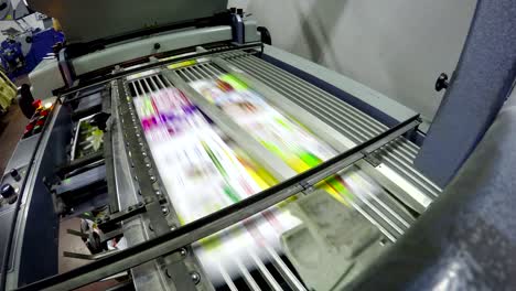 la máquina plegable dobla la hoja offset impresa como parte del folleto de periódico en la imprenta.