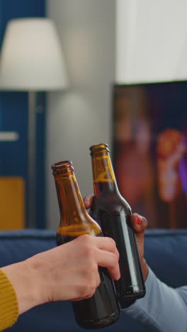 vertical video: close up of young people hands toasting and cheering bottle of beers